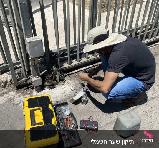 אדם מתקן שער חשמלי עם כלי עבודה